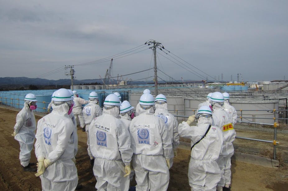 Inspecteurs de l’AIEA devant une aire de stockage d’eau contaminée.